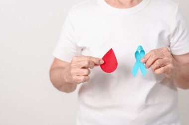 Dünya Diyabet Günü için mavi kurdeleli ve kırmızı kan damlası olan yaşlı kadın, Mavi Kasım Sağlık, Prostat Kanseri Farkındalığı, Kan şekeri kontrolü, insülin, glikoz taraması, bağış ve sağlık kontrolü