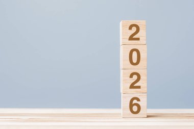 Masa arkasında 2026 metni olan tahta küp bloğu. Çözüm, plan, gözden geçirme, hedef, başlangıç ve yeni yıl tatili kavramları