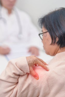 Omuz ve Boyun 'u olan yaşlı kadın ve hastanede danışman doktor. Miyofasyal ağrı sendromu, fibromiyalji, romatizma, skapüler ağrı, boyun omurgası. ergonomik kavram