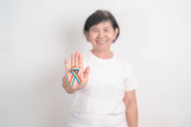 Haziran Gurur Ayı, Nisan Otizm Bilinci, Kanser Farkındalığı, Şubat Dünya Kanser Günü, Ekim Dünya Bakımevi ve Palyatif Bakım Günü konsepti için LGBTQ Gökkuşağı kurdelesine sahip yaşlılar