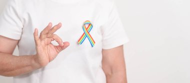 Haziran Gurur Ayı, Nisan Otizm Bilinci, Kanser Farkındalığı, Şubat Dünya Kanser Günü, Ekim Dünya Bakımevi ve Palyatif Bakım Günü konsepti için LGBTQ Gökkuşağı kurdelesine sahip yaşlılar