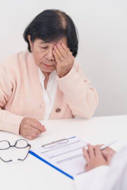 Yaşlı kadın hasta göz ağrısı çekiyor ve göz hastalıkları doktoruna danışıyor. Kıdemli Tıbbi Teşhis. Katarakt, glikoma, Yaşla İlgili Maküler Dejenerasyon, Diyabetik Retinopati, Vitreöz ve Sağlık 