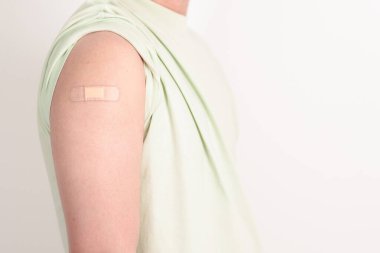 Aşı olduktan sonra bandajlı yetişkin adam. Grip aşısı, HPV, Zoster, IPD, DTP veya Difteri, Tetanos ve Pertusis, MMR, Hepatit B, Covid ve Varicella aşısı