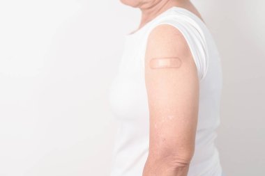 Aşı olduktan sonra bandajlı yaşlı kadın. Grip aşısı, Herpes Zoster, Tetanos, Covid 19 destekleyici, Dang, Ensefalit, Kuduz, Pnömokok, IPD, RSV aşıları 