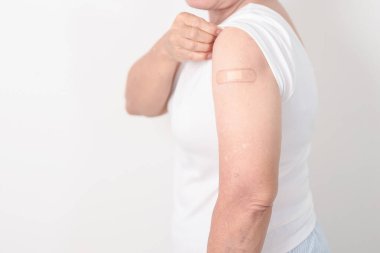 Aşı olduktan sonra bandajlı yaşlı kadın. Grip aşısı, Herpes Zoster, Tetanos, Covid 19 destekleyici, Dang, Ensefalit, Kuduz, Pnömokok, IPD, RSV aşıları 