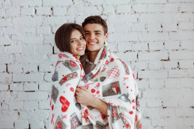 Sıcak ekose kumaşın altında birbirine aşık sevimli bir çift. Sıcaklığın ve birlikteliğin tadını çıkarıyorlar. Güzel bir kadın, duvarın arkasında erkek arkadaşının desteğini hissediyor. Sevgililer Günü konsepti.