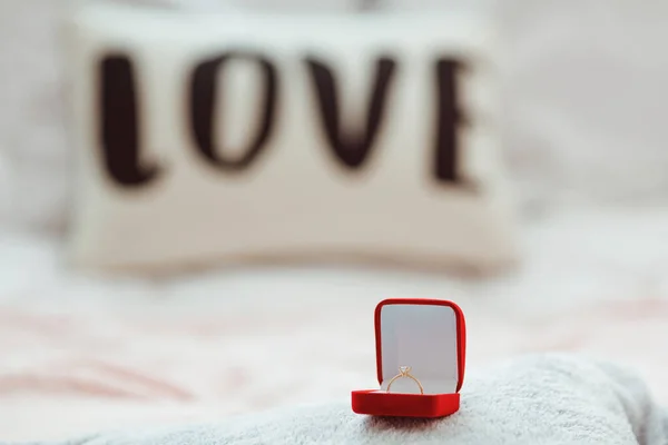 Golden ring in red case on the bed. Romantic gift on Valentines day. Proposal.