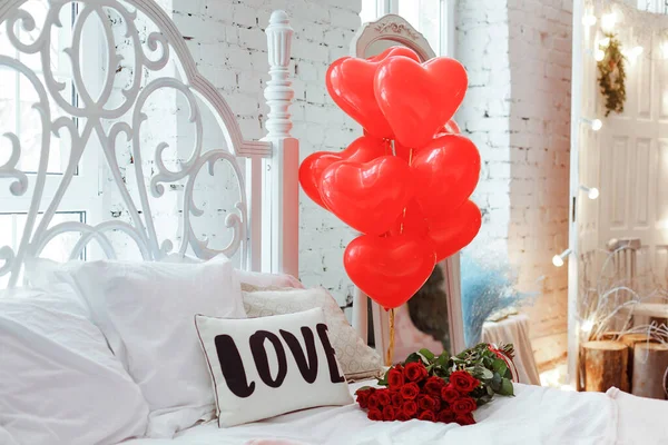 Celebrating Saint Valentine's Day with red roses on bed and air balloons in shape of heart on the bed. Gift for girlfriend on Valentine's day,Women's day.