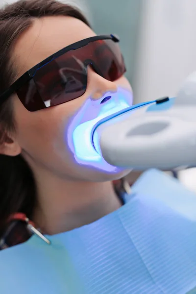 Girl patient in the dental clinic. Teeth whitening UV lamp.