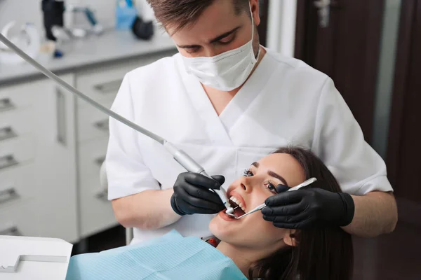 Olgun erkek dişçi, dişçiye giden kadın hastasıyla çalışıyor. Klinikteki dişçi muayenesinde diş hekimliği, tıp endüstrisi sağlık sigortacıları.