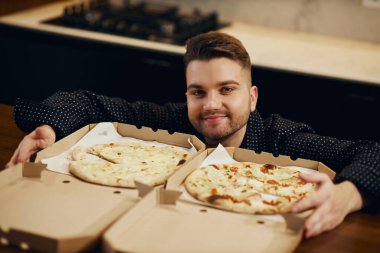 Handsome young man shows how he likes pizza. and prepares to eat it.