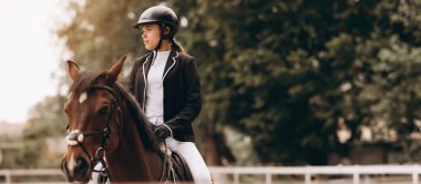 Young woman in special uniform and helmet riding horse. Equestrian sport - dressage.