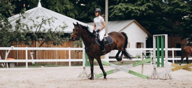 Engelleri aşmak. Sırtında bir binici varken bariyerüzerinden atlayan güzel zarif at