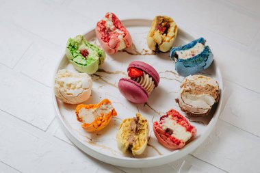 Many big bitten macaroons on a beautiful white plate, on a white background. Photo for content.