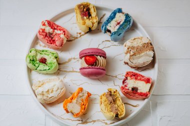 Many big bitten macaroons on a beautiful white plate, on a white background. Photo for content.