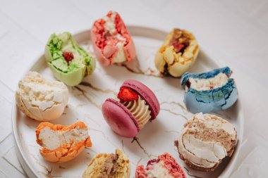 Many big bitten macaroons on a beautiful white plate, on a white background. Photo for content.