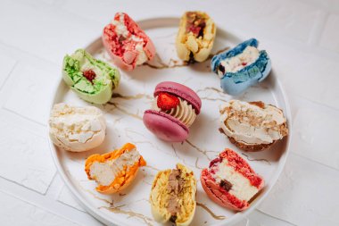 Many big bitten macaroons on a beautiful white plate, on a white background. Photo for content.