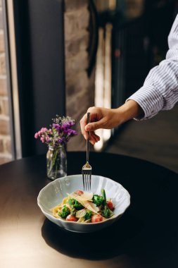 Vegetable pasta with broccoli, tomatoes and asparagus, in a creamy sauce, decorated with parmesan slices.