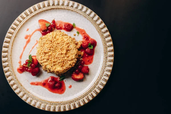 Baked Camembert in nut breading with berry sauce, decorated with strawberries. Restaurant serving of dishes.