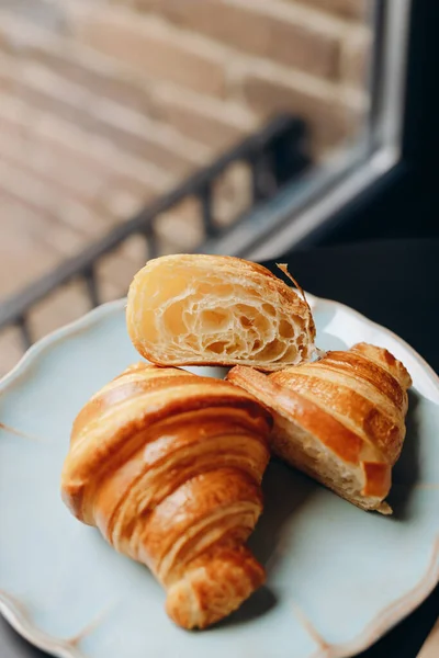 Golden French Croissants in section on a beautiful blue plate.