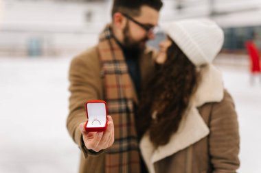 Photo of happy love couple in a figure skating field with a proposal ring