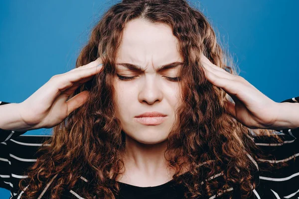 young curly hair woman suffering from headache desperate and stressed because pain and migraine. Hands on head.