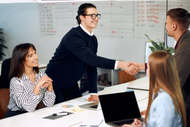 Office workers happily shaking their hands after finished project.