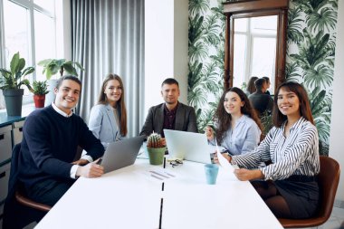 Team of office workers looking at the camera and smiling in the cabinet.
