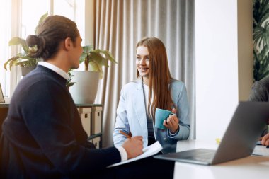 Two young office workers having a talk at the work.