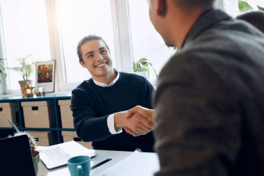 Two business men shaking each others hands and smiling.