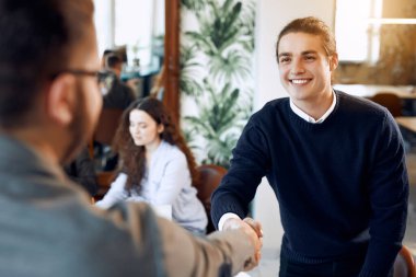 Two business men shaking each others hands and smiling on office meeting.