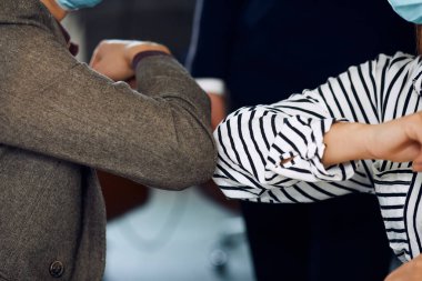 Two office workers are having safe handshake during quarantine.