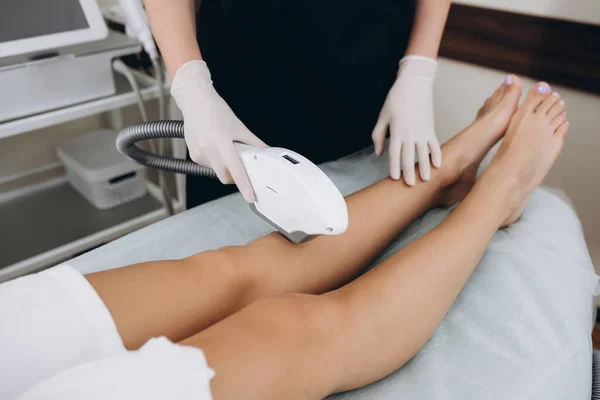 Beautician removes hair on beautiful female legs using a laser. hair removal on the legs, laser procedure at clinic.
