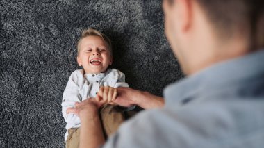 Loving father having fun and tickling his son at home.