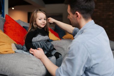 The father helps his daughter to brush the hair. Before going to work and at school, daughter and father spend nice moments.