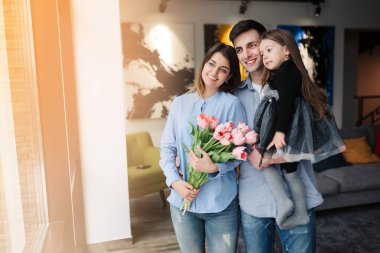 Happy family at home. Give happy mothers! Father and child daughter congratulate mother on the holiday and give flowers. The concept of family happiness and love