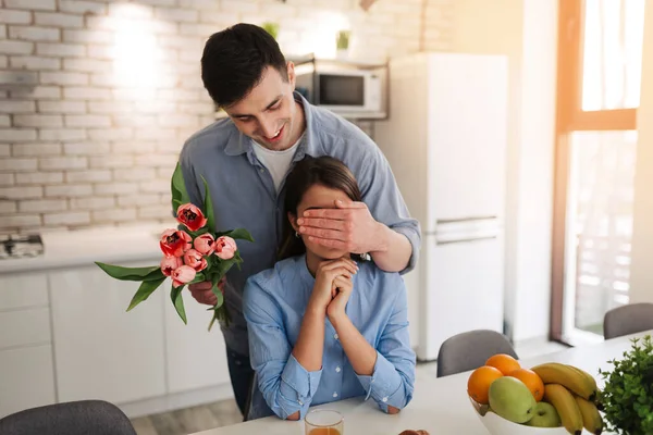 Romantic young man with flowers is covering his girlfriend\'s eyes. Man wants to make surprise for his girl. Romantic concept