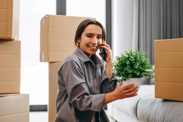 A happy female homeowner is unpacking a parcel with things from a transport company. An American woman unpacks a box of goods. Delivery service, moving to a new house