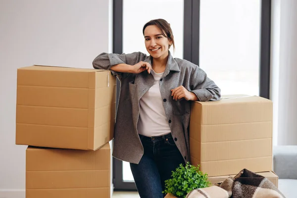 A young girl moved to a new house. Happy is going to spread the boxes. Single lady moves. Real estate purchase, mortgage, delivery service ordering concept.