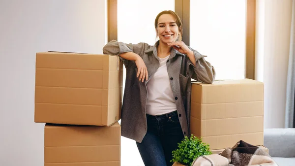 A young girl moved to a new house. Happy is going to spread the boxes. Single lady moves. Real estate purchase, mortgage, delivery service ordering concept.