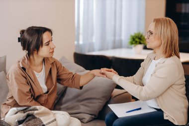 Psikolog randevusunda tatlı bir kız. Psikolog kadın hastasının elini tutuyor. Aile sorunları, ergenlik sorunları. Bir terapistle konuşmak, tavsiye, yardım kavramı.