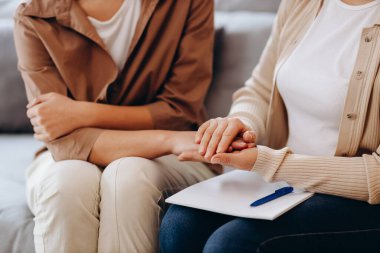 Psikolog randevusunda tatlı bir kız. Psikolog kadın hastasının elini tutuyor. Aile sorunları, ergenlik sorunları. Bir terapistle konuşmak, tavsiye, yardım kavramı.