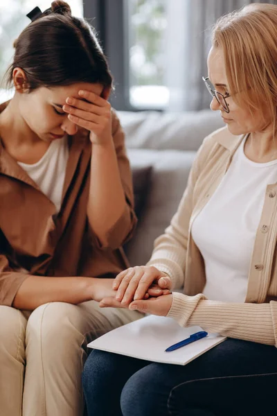 A cute girl at a psychologist\'s appointment. Psychologist woman holding her patient\'s hands. Family problems, teenage troubles. Talking with a therapist, advice, help concept.