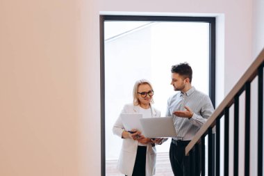 Two people, a man and a woman, are analyzing the success of their company on a laptop.