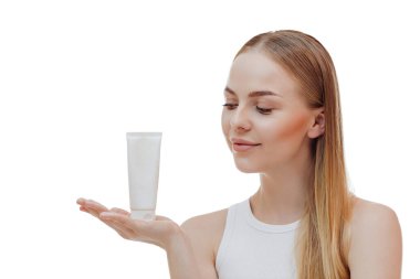 Beauty blonde holds a jar of shampoo or conditioner in her hands. Long blonde hair.