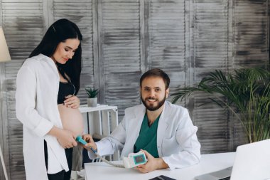 Bir jinekolog hamile bir kadını muayene ediyor. Fetal doppler kalp denetimi