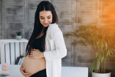 Güzel, mutlu, hamile Afrikalı bir kadın karnına sarılıyor, spor minderinde oturuyor, hamileliğinin tadını çıkarıyor, bedava uzay boşluğu..