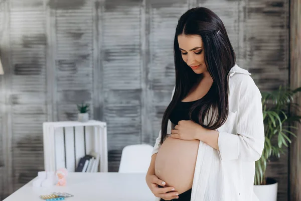 Stock image Beautiful happy pregnant african woman hugging her tummy, sitting on sport mat, enjoying her pregnancy, free space.