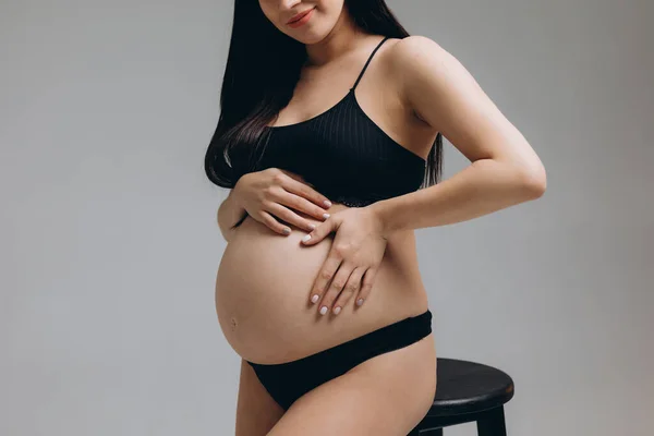 Schwangere Berührt Ihren Bauch Und Posiert Auf Grauem Hintergrund — Stockfoto