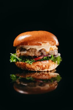 Sığır pirzolası, marul, Kırım soğanı, domates, salatalık turşusu, Çedar peyniri, hardal, sert sos.